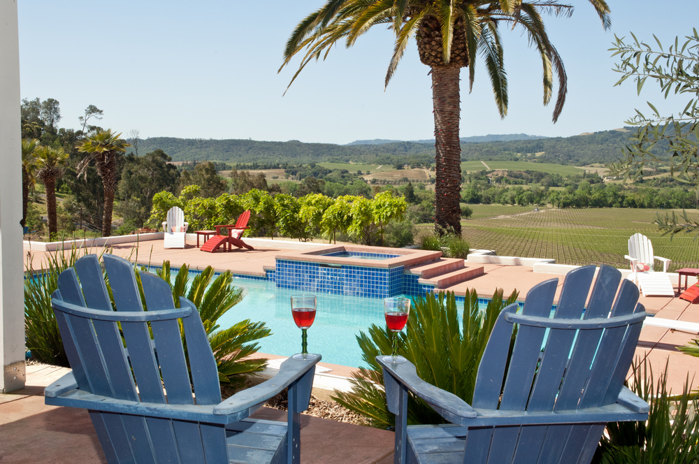 Two lounge chairs & drinks overlooking a pool and palm tree